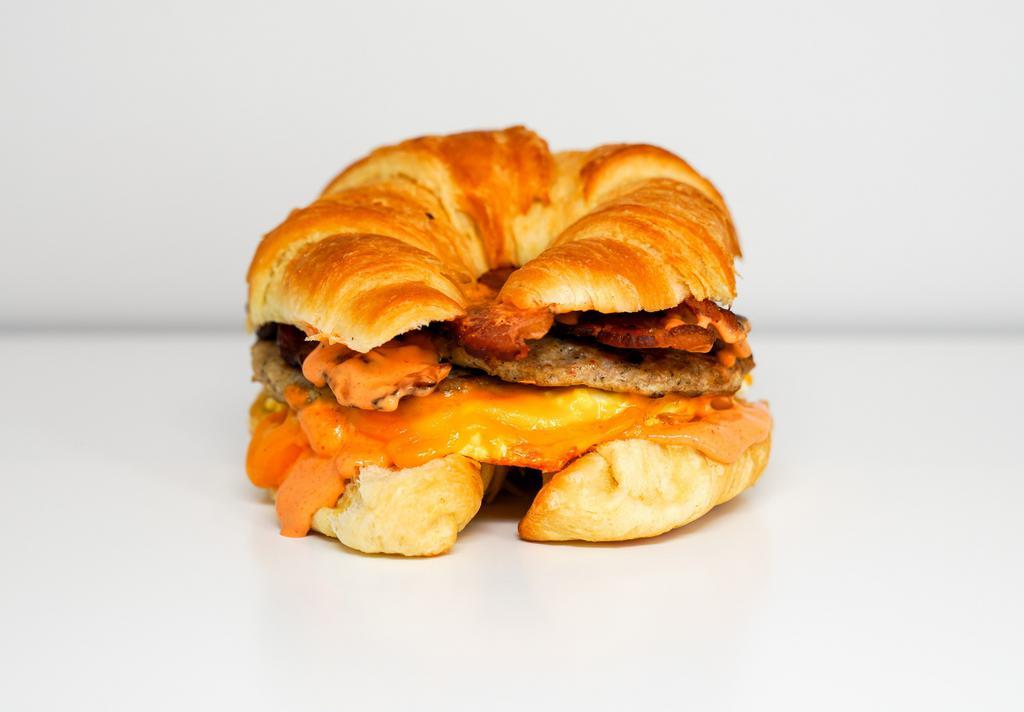 Croissant, Bacon, Sausage, Egg & Cheese Sandwich · 2 scrambled eggs, melted cheese, smoked bacon, breakfast sausage, and Sriracha aioli on a warm croissant.