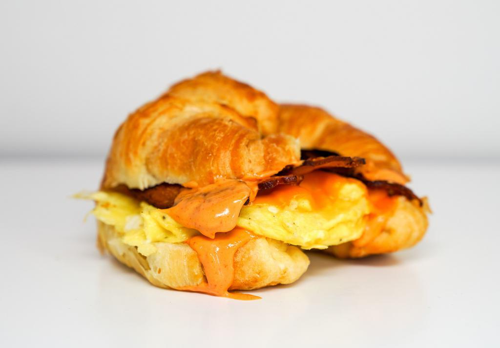 Croissant, Bacon, Egg, & Cheddar Sandwich · 2 scrambled eggs, melted Cheddar cheese, smoked bacon, and Sriracha aioli on a warm croissant.