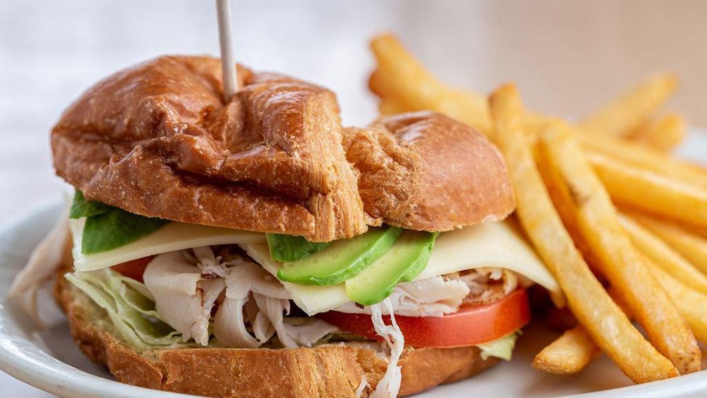 Turkey Avocado Croissant · A flaky croissant piled high with hand-carved turkey breast, fresh avocado, pepper jack cheese, lettuce, tomatoes and mayo. Served with choice of side.
