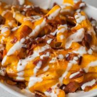 House Fries · Crispy cut fries topped with melted cheddar cheese, bacon, and our homemade Creamy Ranch Dre...