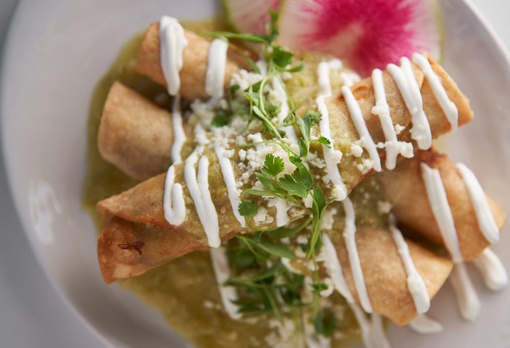 Sonora Style Taquitos · Crispy corn rolled tacos filled with braised shredded beef or machaca chicken, pasilla verde salsa, Cotija cheese, cream, and cilantro.