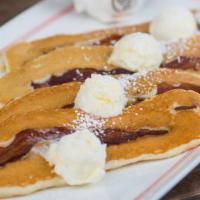 Bacon Pancakes · Four pancakes topped with whipped butter and powdered sugar
