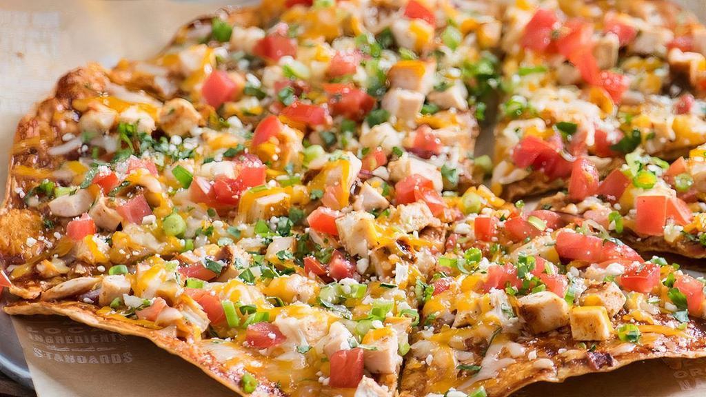 Bbq Chicken Pizza · Chipotle BBQ sauce, cheese, cotija cheese, tomatoes, red onion, green onion, cilantro, and chipotle crust