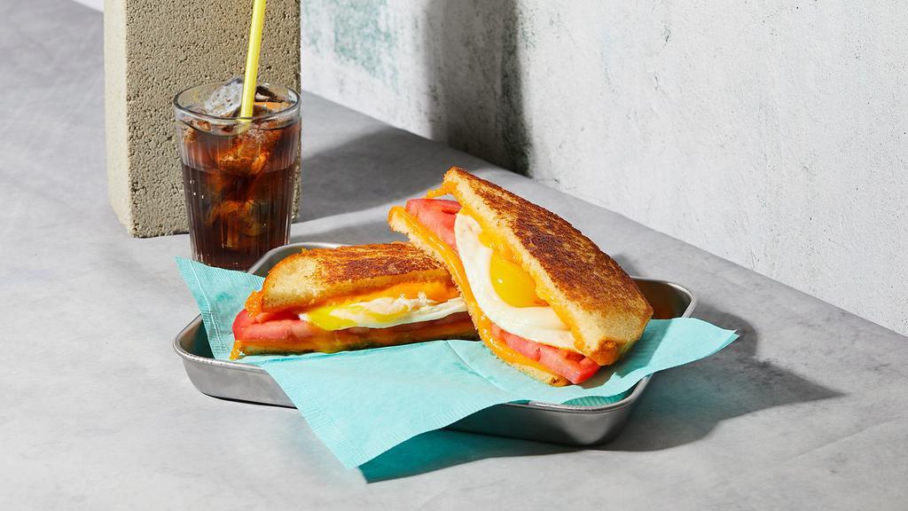 The Breakfast · Melted Cheddar cheese with a scrambled egg and tomato grilled between two slices of buttered bread.