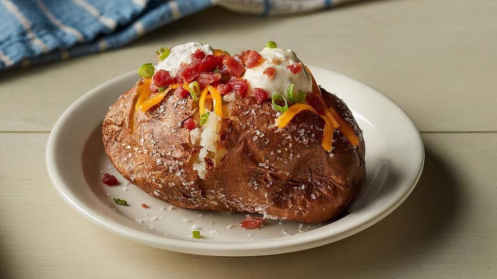 Loaded Baked Potato · Baked Potato topped with shredded Colby Cheese, bacon pieces, whipped butter, Sour Cream and chopped green onions..