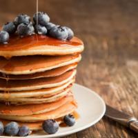 3 Fluffy Blueberry Hotcakes · Fresh fluffy pancakes topped with blueberries with a side of syrup and butter.