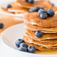 Buttermilk Berries Pancakes · Three fluffy buttermilk pancakes topped with berries and whipped cream. Maple syrup and butt...