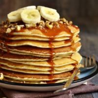 Buttermilk Banana Pancakes · Three fluffy buttermilk pancakes topped with bananas and whipped cream. Maple syrup and butt...