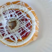White Chocolate Raspberry Cheesecake · Raised yeast donut topped with raspberry, cream cheese icing, and white chocolate drizzle