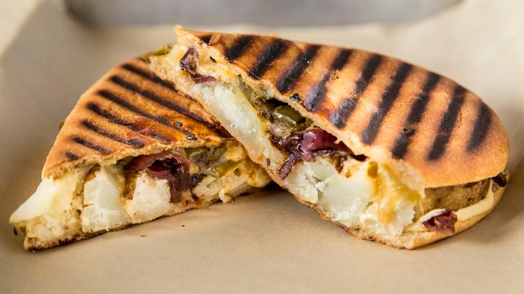 Golden Panini · Roasted garlic golden potatoes, housemade garlic/mustard aioli, grilled bell peppers, onions, and cheddar/jack cheese.