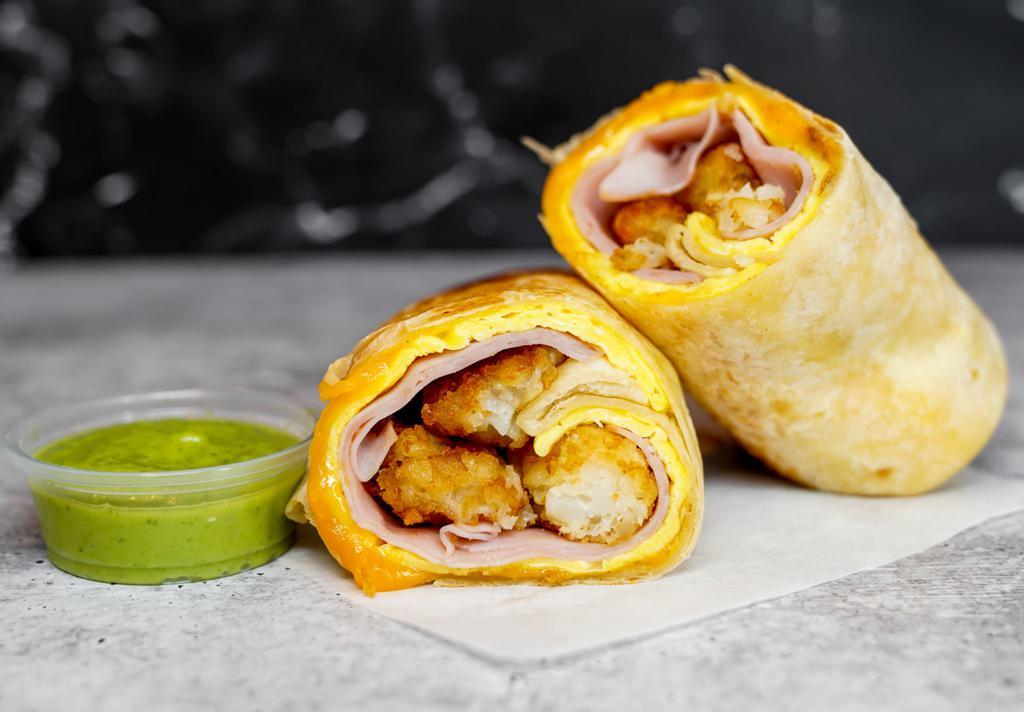 Ham, Egg, & Cheddar Breakfast Burrito · 3 fresh cracked, cage-free scrambled eggs, melted Cheddar cheese, sliced ham, and crispy potato tots wrapped in a toasted 12” flour tortilla. Comes with avocado salsa verde side.