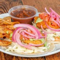 Baja Fish Tacos · Two tacos topped with cabbage, charred corn pico and cilantro on warm flour tortillas.