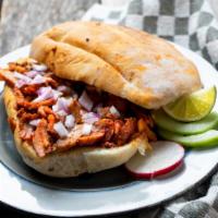 Lonche De Pierna · Special sandwich prepared with sourdough bread and topped with pulled pork, sour cream, lett...