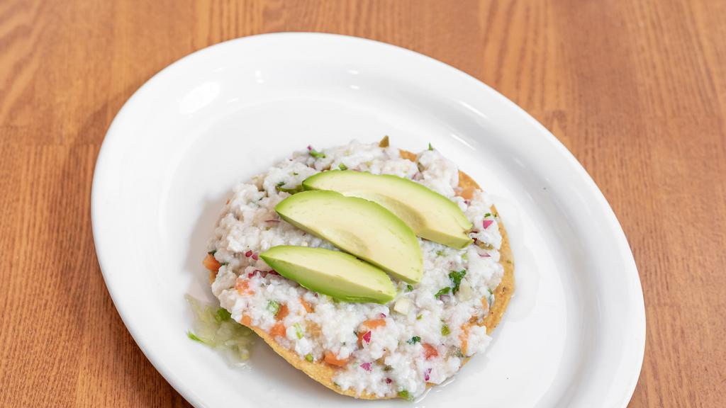 Tostada De Ceviche · Fish marinated with lime juice, jalapeno, red onion, carrots and topped with avocado slices.