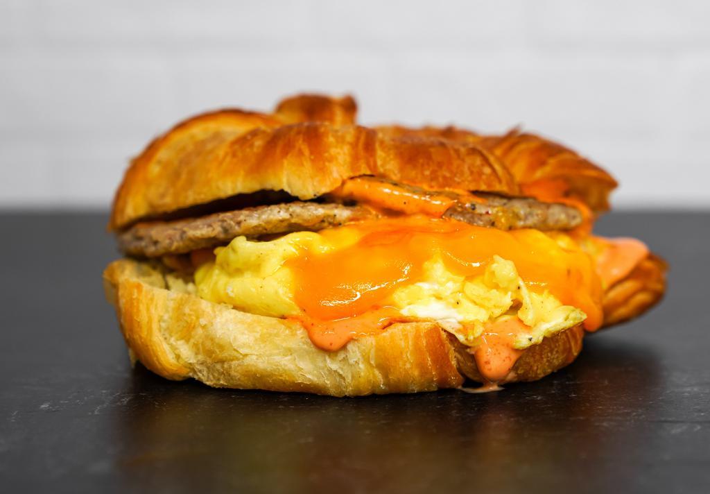 Sausage, Egg And Cheddar Sandwich · 2 fresh cracked cage-free scrambled eggs, melted Cheddar cheese, breakfast sausage, and Sriracha aioli on a warm croissant