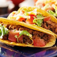 Ground Beef Hard Taco · Taco made of ground beef, cheese, tomatoes, lettuce, and hot sauce on the side.
