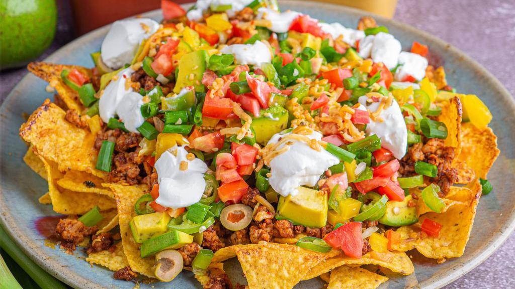 Nachos Supreme · Warm and crispy tortilla chips topped with melted cheese, hearty beans, and house made pico de gallo.