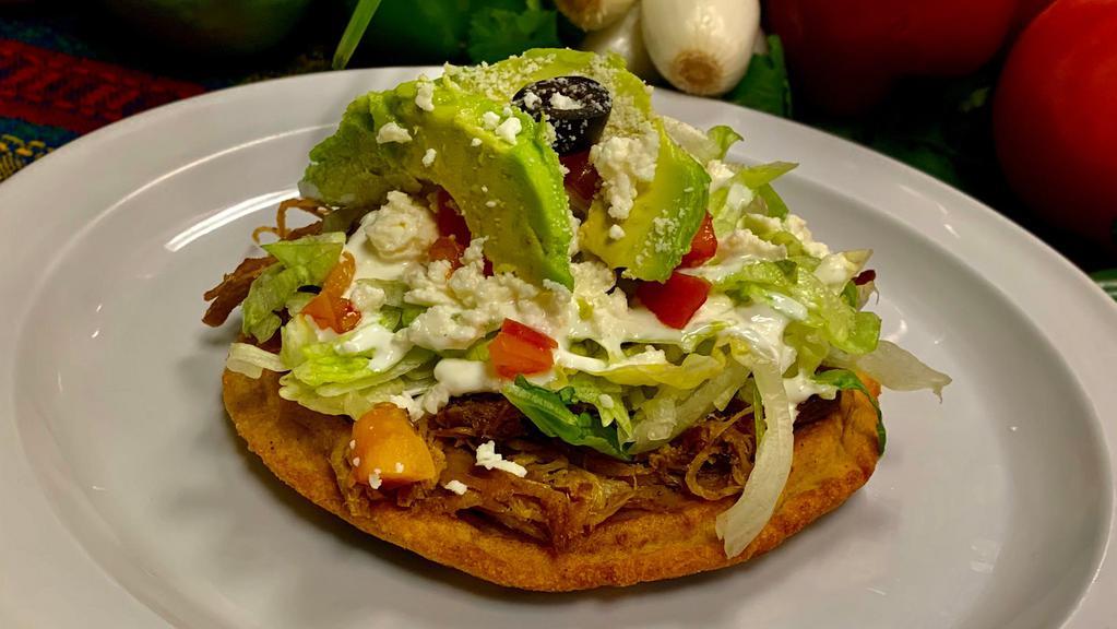 Sope · Meat, beans, onions, lettuce, Mexican cheese, sour cream, tomato, avocado slices, one olive.
