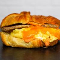 Croissant, Sausage, Egg, & Cheddar Sandwich · 2 scrambled eggs, melted Cheddar cheese, breakfast sausage, and Sriracha aioli on a warm cro...