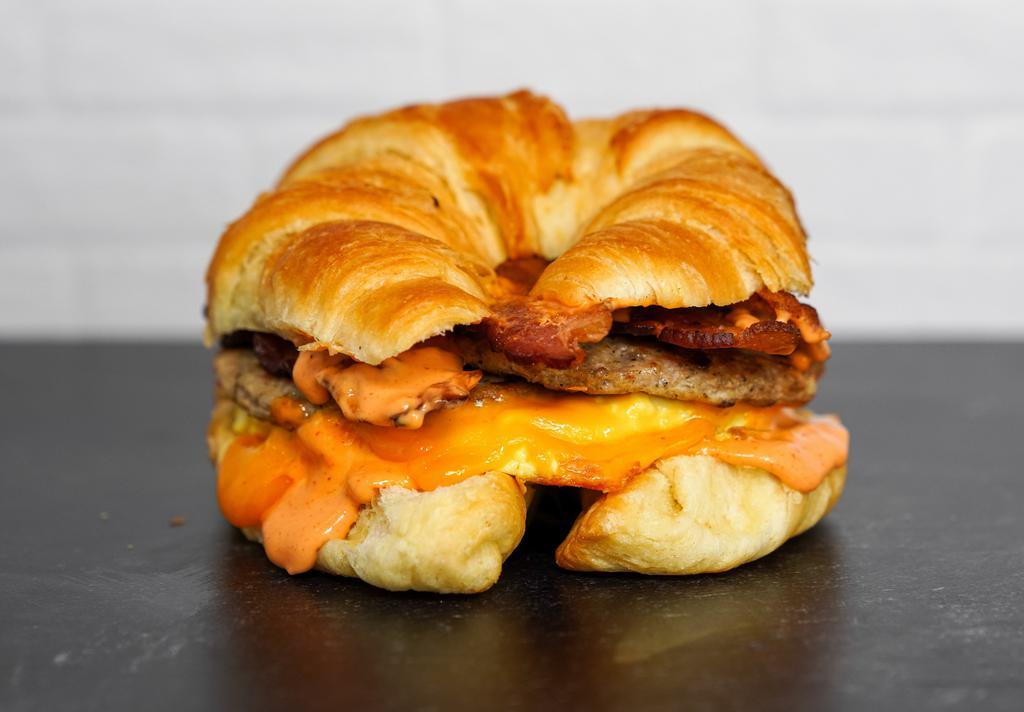 Croissant, Bacon, Sausage, Egg & Cheddar Sandwich · 2 scrambled eggs, melted Cheddar cheese, smoked bacon, breakfast sausage, and Sriracha aioli on a warm croissant.