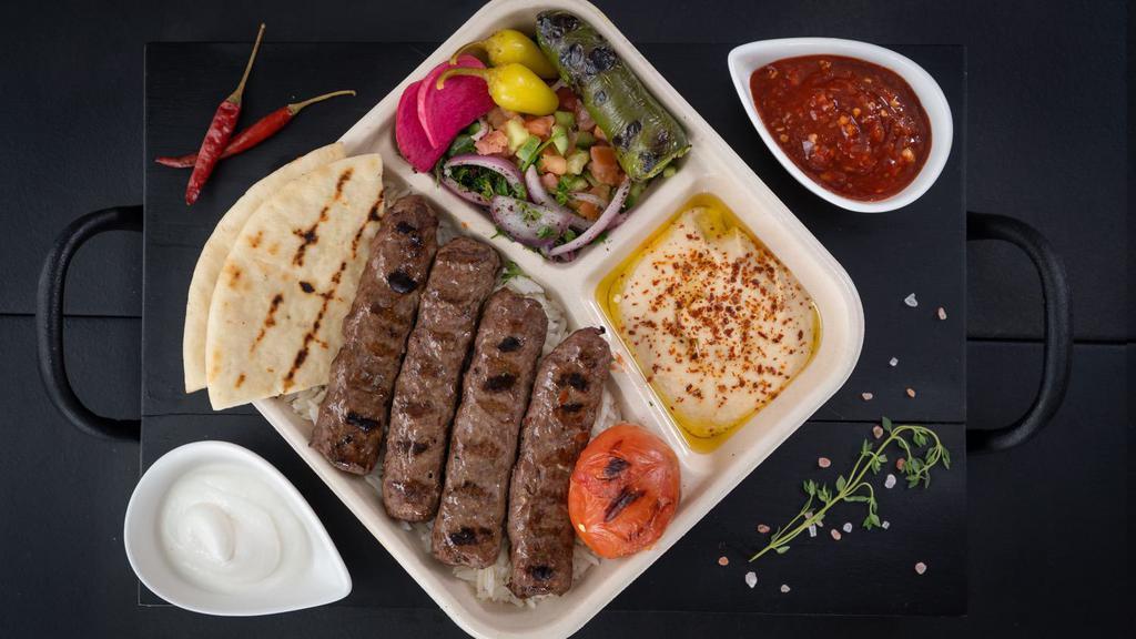 Beef Lule Kebab Plate · Two skewers of spiced ground beef, hummus, basmati rice, shepherd salad, grilled tomato and jalapeño, onion & parsley, pickle turnip and chili peppers, served with pita breads, garlic sauce on the side.