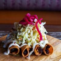 Chicken Taquito · Four crispy shredded chicken taquitos, topped with curtido and our green tomatillo sauce.