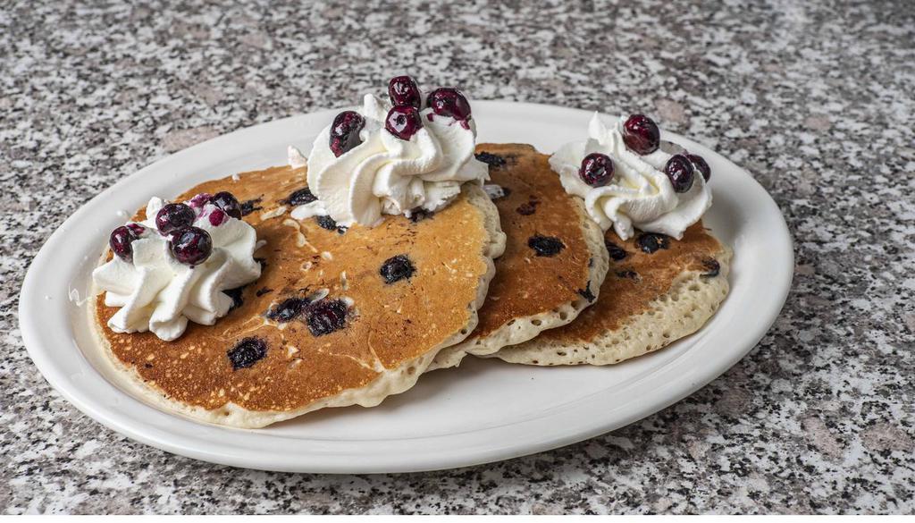 Blueberry Hotcakes · Full stack, bursting with blueberries and topped with whipped cream