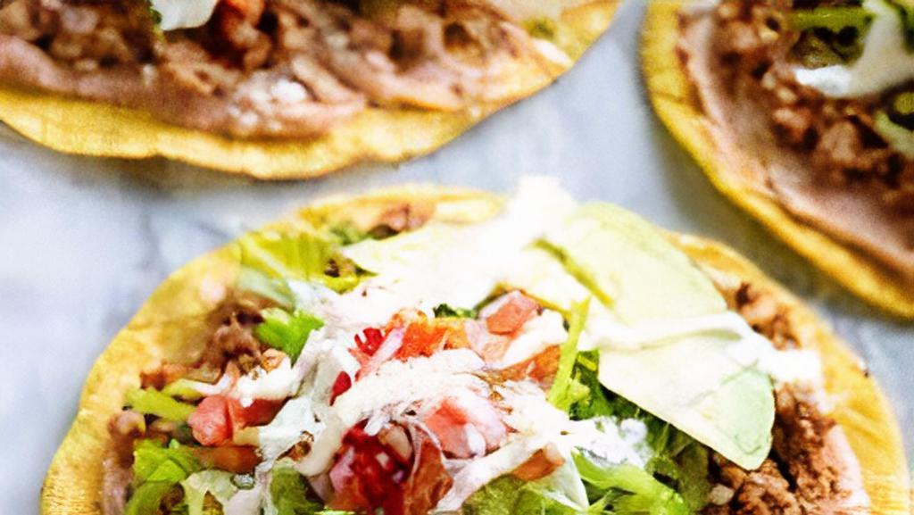 Tostada · Choice of meat, beans, lettuce, sour cream, guacamole and cheese.