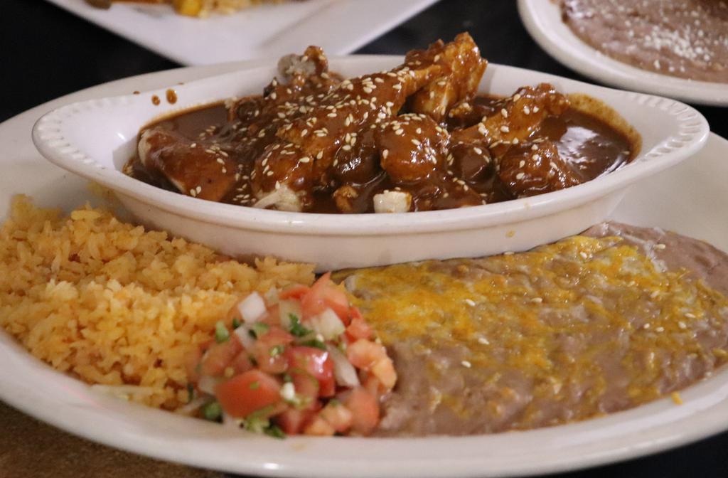 Mole Con Pollo · Strips of chicken breast slow cooked in our mole. Is a complex dish of dried chiles, nuts, seeds, vegetables, spices, and chocolate carefully woven together. Served with rice, beans and tortillas.
