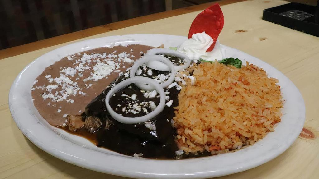 Enchiladas De Mole · Two grilled corn enchiladas filled with shredded chicken made with our freshly mole sauce. Served with rice and beans. Garnished with fresh cheese, sour-cream and onions.
