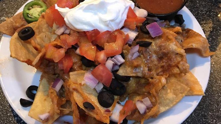 Nacho'S Grande · White corn tortilla chips, refried beans, choice of tostada chicken, or seasoned ground beef, tomatoes, onion, olives, with melted Jack and Cheddar cheeses, salsa, sour cream, guacamole, and enchilada sauce.
