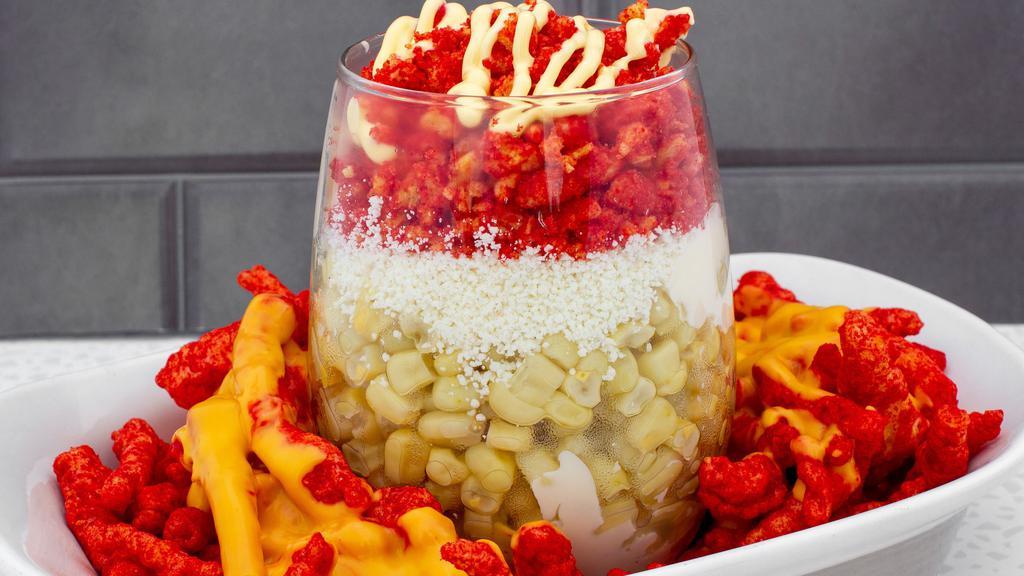 Flaming Corn · A cup of corn with mayo, Cheetos, butter on top of a plate of hot Cheetos with nacho cheese.