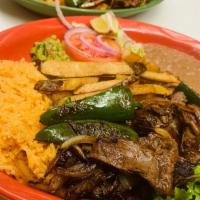 Carne Asada Plate · Full plate of strips of special flat steak served with fries, beans, and salad.