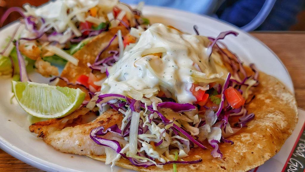 Grilled Fish · Three grilled fish tacos in a warm corn tortilla, shredded cabbage, cheddar cheese, salsa fresca then drizzled with fresh crema.
