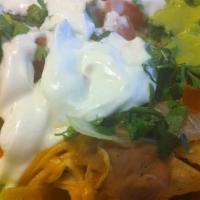 Nachos · Freshly made tortilla chips topped with cheese, refried beans, red ranchera sauce, tomatoes,...