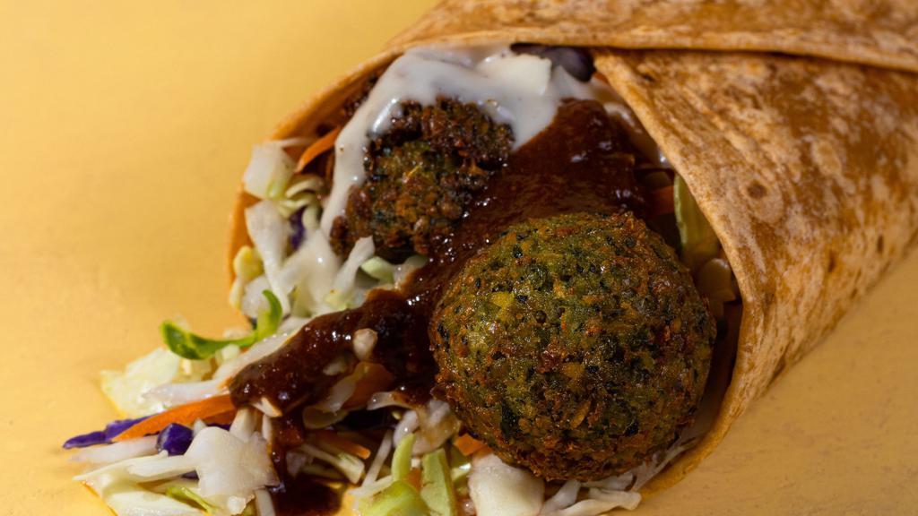Falafel Wrap · The Falafel Wrap comes with, hummus, harissa sauce, cabbage mix, falafel and lemon tahini wrapped in a warm sundried tomato tortilla.