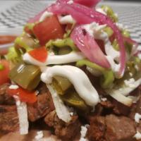 Chef'S Carne Asada Tostada · Carne asada, re fried beans, organic wild cactus salad, lettuce, sour cream, cotija queso, g...