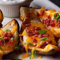 Made-From-Scratch Loaded Potato Skins · Topped with bacon, shredded cheddar cheese, green onions & served with sour cream.