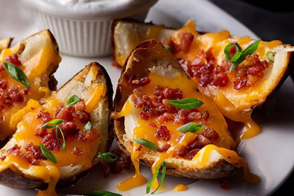 Made-From-Scratch Loaded Potato Skins · Topped with bacon, shredded cheddar cheese, green onions & served with sour cream.