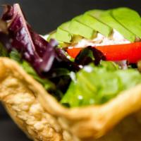 Tostada Salad · A tostada bowl filled with spring mix, tomato, avocado, rice, refried beans, sour cream, and...