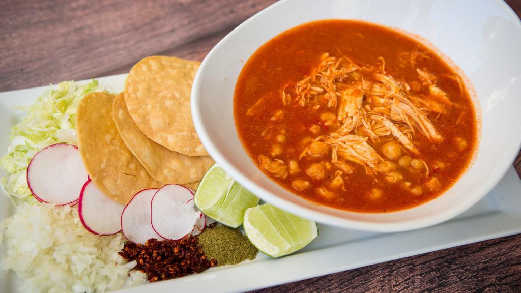 Pozole · Chile guajillo broth with hominy (blanched corn kernels), spices and shredded chicken. Served with corn tostadas, cabbage, lime, oregano, Chile de arbol, onions, and radish slices on the side.