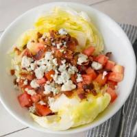 Wedge Salad · A wedge of iceberg, chopped crisp bacon, tomatoes, and blue cheese crumbles with blue cheese...