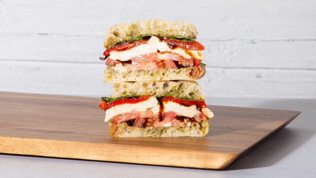 Mozzarella Caprese · Fresh mozzarella with sliced tomato, roasted red peppers, mixed greens, basil pesto, and balsamic on your choice of bread.