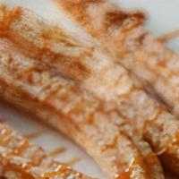 Churros · Cinnamon churros topped with chocolate shavings and dusted with powder sugar.