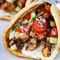 Gyro · Four pieces of gyro meat, tzatziki, onions and tomatoes on pita bread.