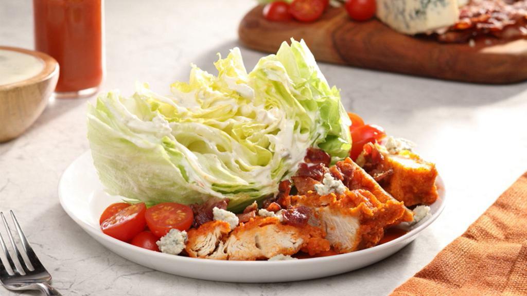 Buffalo Wedge Salad (Grilled) · Buffalo Grilled Chicken tossed with Buffalo sauce over iceberg wedge, tomatoes, bacon, blue cheese dressing and crumbles.