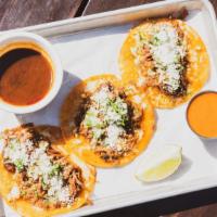Birria Tacos · 3 outrageous tacos filled with a 18 hour braised short rib.  Highlighted with cilantro, onio...