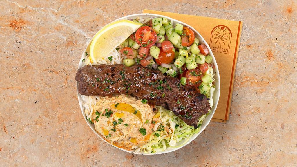 Beef Kebab Rice Bowl · Ground beef over basmati rice with hummus, diced cucumber and tomato salad, shredded green cabbage and a drizzle of tahini sauce.