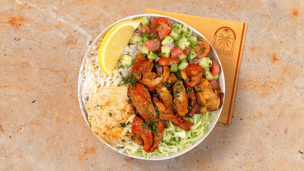 Chicken Shawarma Rice Bowl · Savory chicken shawarma over basmati rice with hummus, diced cucumber and tomato salad, shredded green cabbage and a drizzle of tahini sauce.
