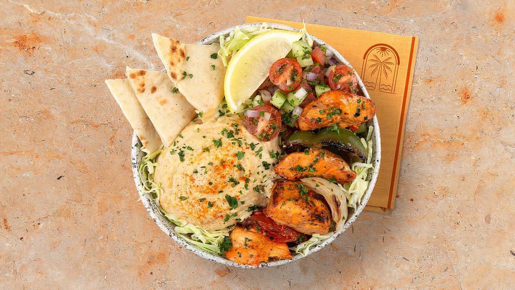 Chicken Kebab Hummus Bowl · Grilled chicken over hummus, diced cucumber and tomato salad, shredded green cabbage and a drizzle of tahini sauce.